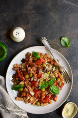Fusilli pasta with tomatoes, eggplants and olives. Top view with copy space.