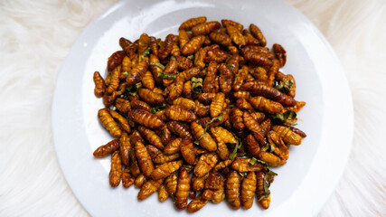 Crispy fried insects worm with salt 
 , Close-up Oily taste and salty silkworms. , Insect food , topview