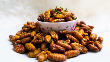 Silkworm pupa fried , Close-up of fried bamboo worms for sale in the market.