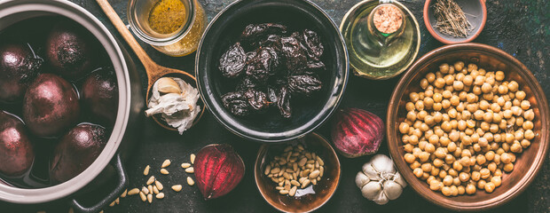 Vegan food in bowls: beetroot , chickpeas, dates, oil, garlic and pine nuts on dark kitchen table. Hummus cooking ingredients.Top view. Banner.