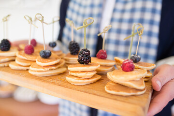 female holding mini pancakes with berries and powered sugar. party time with pancakes!