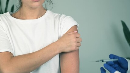 Professional male doctor in medical gloves giving flu vaccine injection to female patient. Young woman getting COVID-19 shot during vaccination campaign