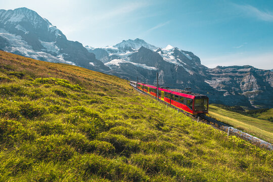Electric modern tourist train and snowy mountains in background, Switzerland