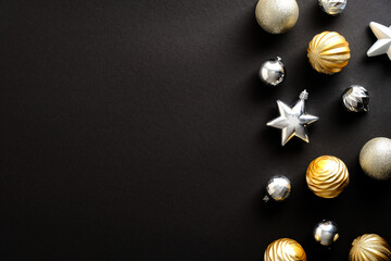 Luxury Merry Christmas and Happy New Year greeting card design. Golden and silver Christmas baubles on dark black background. Flat lay, top view, copy space.