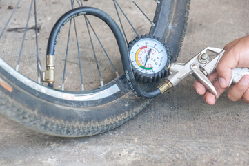 Close up mechanic's hand  Measure quantity Inflated Rubber tires bicycle. mechanic inflating tire...