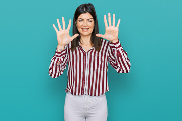 Beautiful brunette woman wearing striped shirt showing and pointing up with fingers number nine...