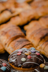 muffins with chocolate and colorful smarties on it. in the background peaks in different flavors of chocolate. delicious sweet pastry for breakfast.