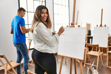 Two students smiling happy painting at art school.