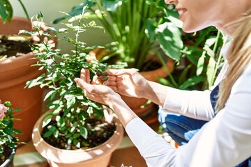 Obraz premium Young blonde woman smiling happy working at home terrace garden.