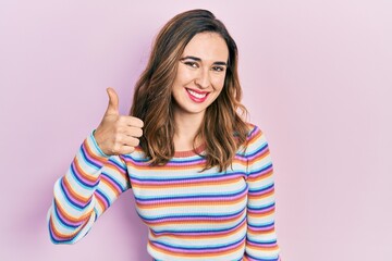 Young hispanic girl wearing casual clothes doing happy thumbs up gesture with hand. approving expression looking at the camera showing success.