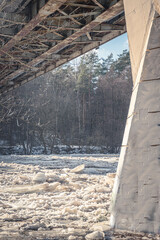 Large pieces of ice in Neris river. Urban view under Žvėrynas pedestrian bridge, Vilnius, Lithuania. Selective focus on the debacle, blurred background.