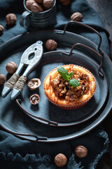 Tasty and sweet walnut cheesecake on dark plate.