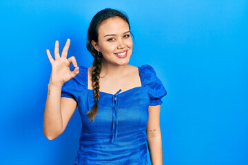 Fototapeta premium Young hispanic girl wearing casual clothes smiling positive doing ok sign with hand and fingers. successful expression.