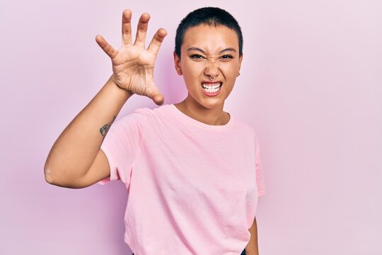 Beautiful hispanic woman with short hair wearing casual pink t shirt smiling funny doing claw gesture as cat, aggressive and sexy expression