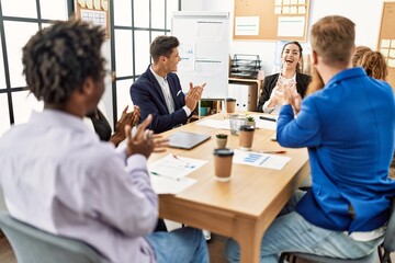 Group of business workers smiling and clapping to partner at the office.