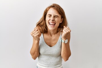 Fototapeta premium Beautiful caucasian woman standing over isolated background excited for success with arms raised and eyes closed celebrating victory smiling. winner concept.