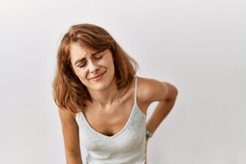 Fototapeta premium Beautiful caucasian woman standing over isolated background suffering of backache, touching back with hand, muscular pain
