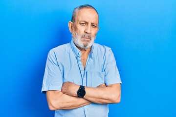 Handsome senior man with beard wearing casual blue shirt skeptic and nervous, disapproving expression on face with crossed arms. negative person.