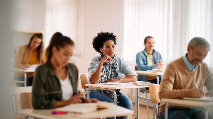 African American female student pays attention on class at lecture hall.