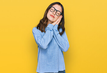 Young beautiful woman wearing casual clothes and glasses sleeping tired dreaming and posing with hands together while smiling with closed eyes.