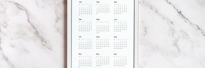 tablet computer with an open app of calendar for unspecified date year without date on a gray marble background. concept business or to do list goals with technology using. top view, flat lay. banner