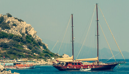 Luxury twin-masted sailing vessel on anchor off a Mediterranean beach