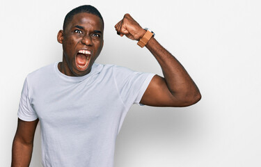 Young african american man wearing casual white t shirt angry and mad raising fist frustrated and furious while shouting with anger. rage and aggressive concept.