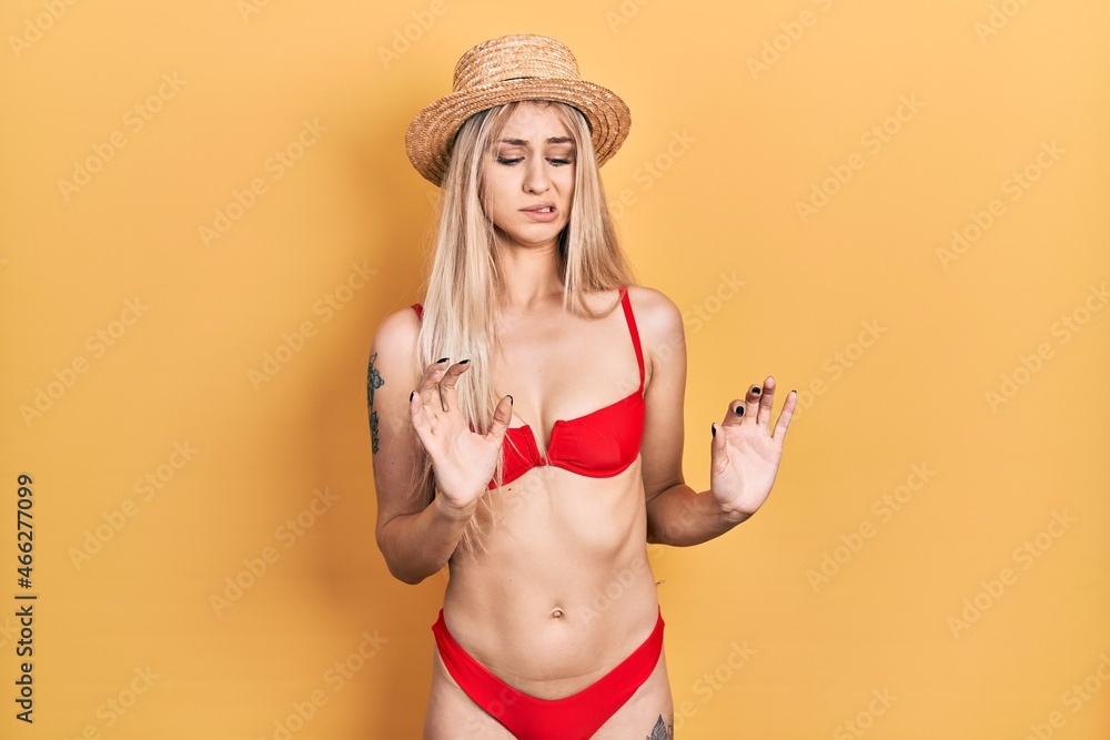 Canvas Prints young caucasian woman wearing bikini and summer hat disgusted expression, displeased and fearful doi