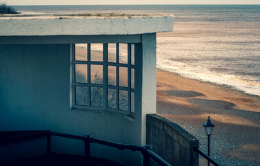 A concrete and glass lookout shelter overlooking the sandy beach at Cromer in Norfolk, UK