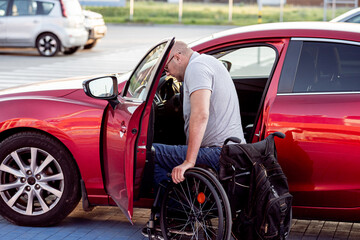 person with a physical disability getting in red car from wheelchair