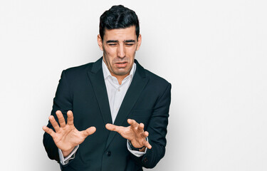 Handsome hispanic man wearing business clothes disgusted expression, displeased and fearful doing...