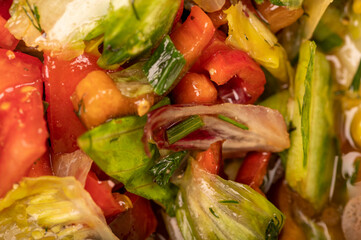 Vegetable salad of sliced tomatoes, cucumbers, sweet peppers, radishes and herbs, close-up, selective focus.