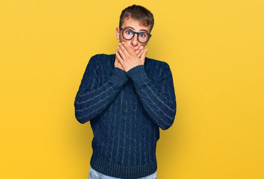 Young blond man wearing casual clothes and glasses shocked covering mouth with hands for mistake. secret concept.