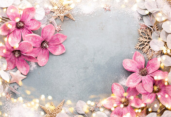 New Year celebration and Christmas background with pink flowers, snow, stars and Christmas decorations top view.