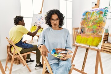 Young hispanic woman at art studio skeptic and nervous, frowning upset because of problem. negative...