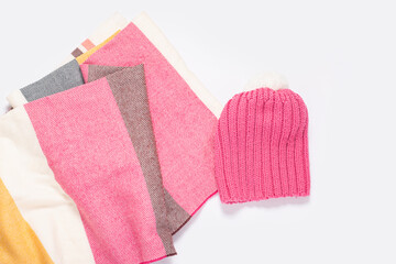 Pink hat and striped scarf on a white background. Top view, flat lay.