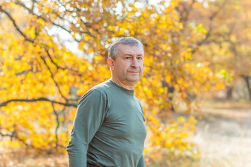 Naklejka na ściany i meble Mature European older man at nature, philosophical portrait, at autumn park