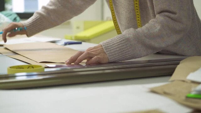 Tailoring process. Woman seamstress drawing sewing mold on paper. Marking cloth pattern for the dress