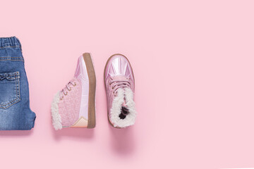 Boots and blue jeans for a girl on a pink background. Top view, flat lay.