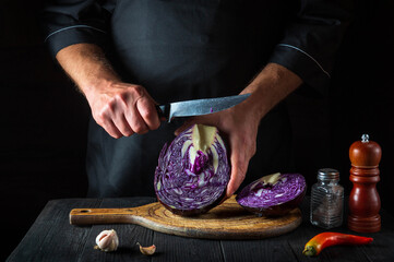The cook is cutting red cabbage with a knife. Cooking vegetable salad in the restaurant kitchen. Vegetable diet idea.