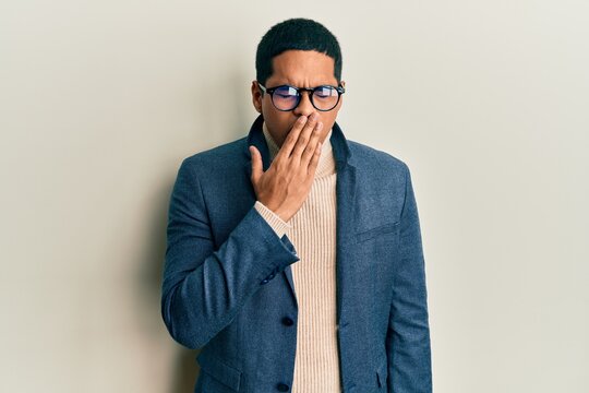 Young handsome hispanic man wearing elegant clothes and glasses bored yawning tired covering mouth with hand. restless and sleepiness.
