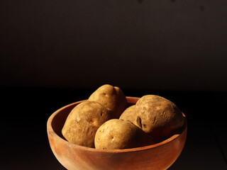 Fresh potato on a wooden bowl