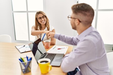 Two business workers smiling happy celebrating agreement with handshake at the office.