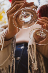 two glasses of red wine in the hands of a young girl close-up against the background of the forest and sky. love story outdoors. bottom view