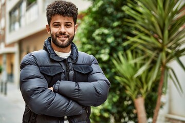 Young arab man smiling with crossed arms outdoor at the town