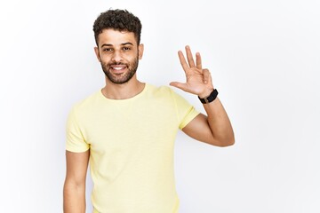 Arab young man standing over isolated background showing and pointing up with fingers number four while smiling confident and happy.