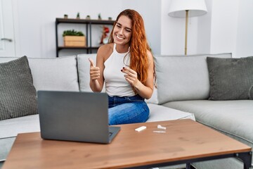 Obraz premium Young redhead woman doing coronavirus infection nasal test smiling happy and positive, thumb up doing excellent and approval sign