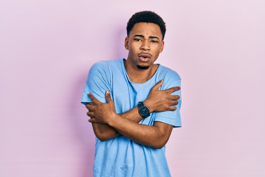 Young african american man wearing casual blue t shirt shaking and freezing for winter cold with sad and shock expression on face