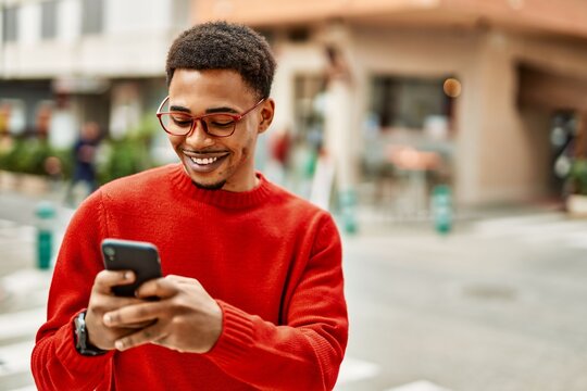 Handsome african american man outdoors using smartphone typing a message