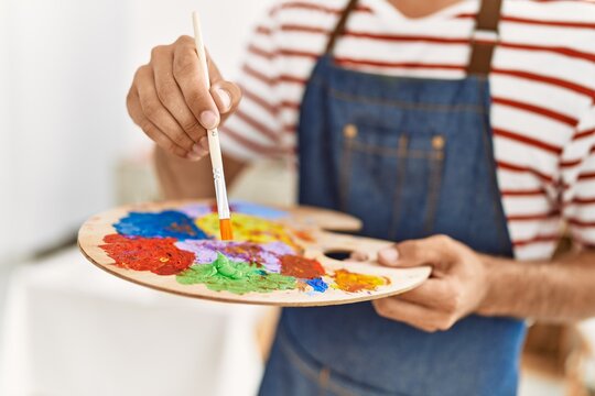 Young hispanic man mixing color on palette at art studio